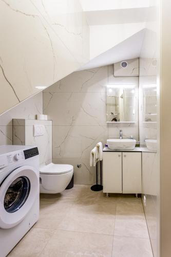 a white bathroom with a toilet sink and a washing machine at Kuća Ružica in Omiš