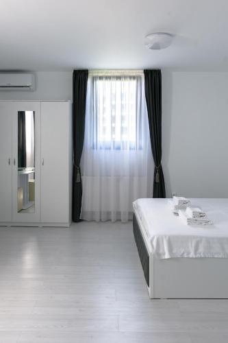 a white bedroom with a bed and a window at Hotel Palas Grand View in Iaşi