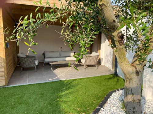 un patio avec un canapé et des chaises à côté d'un arbre dans l'établissement Maison proche plage présidents, à Les Sables-dʼOlonne