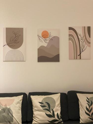 four paintings on a wall above a couch at Ma Home in Cinisi