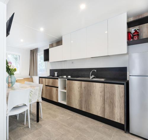 a kitchen with white cabinets and a table with white chairs at Camping Bungalow Lido in Capoliveri
