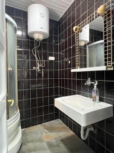 a black tiled bathroom with a sink and a mirror at Top House in Šabac