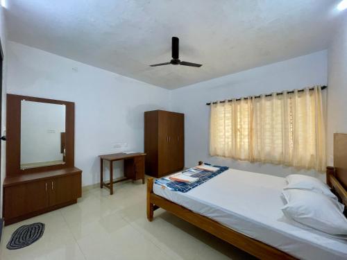 a bedroom with a bed with a ceiling fan and a mirror at Weekly Stays in Manipal in Manipala