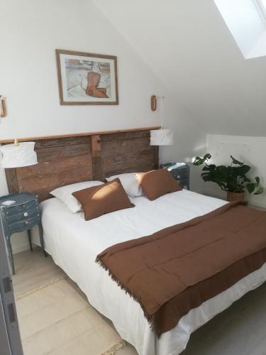 1 dormitorio con 1 cama blanca grande con almohadas marrones en La mansarde, en Nozay