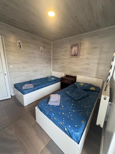two twin beds in a room with wooden walls at Casa Alex in Piteşti