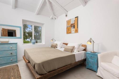 a white bedroom with a bed and a blue dresser at Villa Dassos by Villa Plus in Skinária