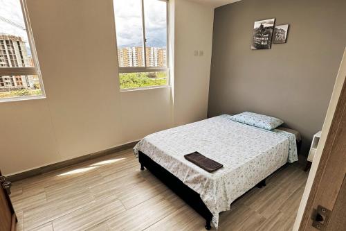 a small bedroom with a bed and two windows at Moderno apartamento con balcon y vista al guadual, Piscina y parqueadero in Pereira