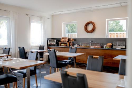 a dining room with tables and chairs and windows at Hotel Donau-Ries in Mertingen