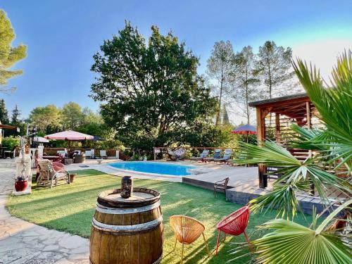 a backyard with a barrel and chairs and a pool at L'escale chambres d'hôtes et gîte in Draguignan