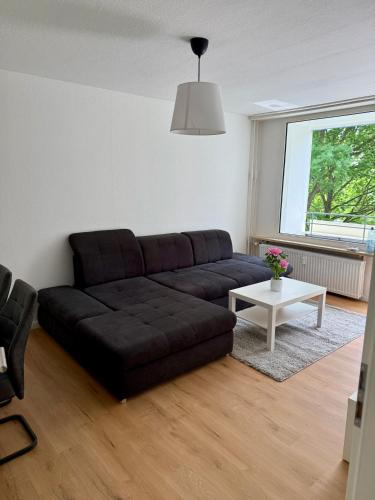 a living room with a black couch and a table at Comfy Modern 4-Bed Apartment, WiFi, 20min DUS, 5min A46 in Erkrath