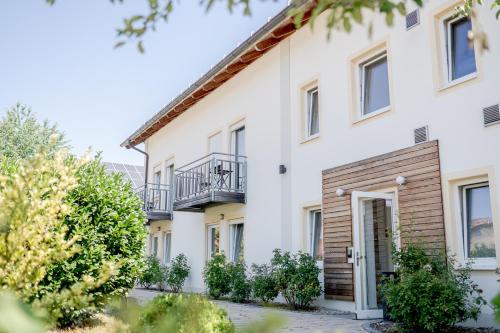 a white house with a balcony and trees at Hotel Donau-Ries in Mertingen