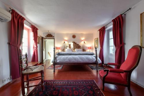 a bedroom with red curtains and a bed and a chair at Le Hameau in Saint-Paul-de-Vence