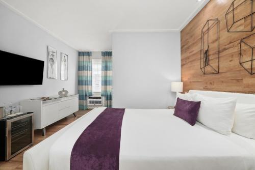 ein Schlafzimmer mit einem großen weißen Bett und einem Flachbildfernseher in der Unterkunft Shelley Hotel in Miami Beach