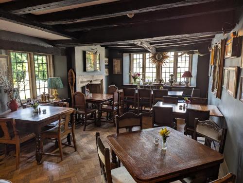 a restaurant with wooden tables and chairs and windows at The Crown at Shipton in Shipton under Wychwood