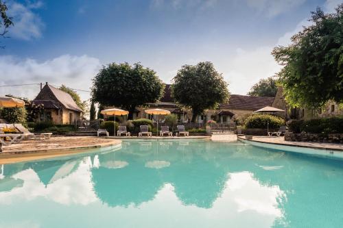 une piscine avec de l'eau bleue devant une maison dans l'établissement Hôtel de la Ferme Lamy, à Meyrals