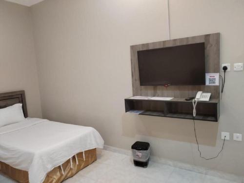 a bedroom with a bed and a tv on a wall at مركز السراج للوحدات المخدومة in Jeddah