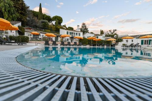 a swimming pool with orange umbrellas in a resort at Le Hameau in Saint-Paul-de-Vence