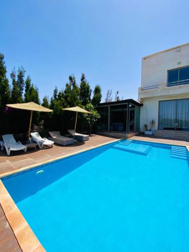 a swimming pool with two umbrellas and a house at Villa Sunset Moulay Bouzerktoun in Essaouira