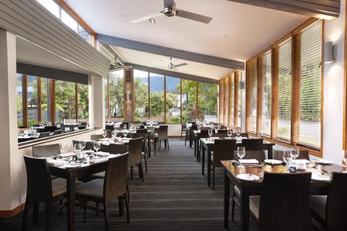a dining room with tables and chairs and windows at Scenic Hotel Franz Josef Glacier in Franz Josef