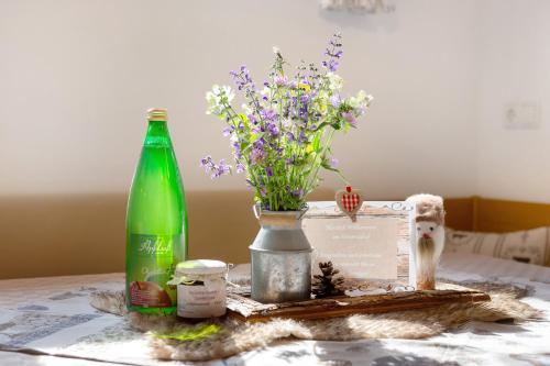 a bottle and a vase of flowers on a table at Untertalhof in Castelrotto