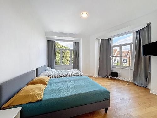 a bedroom with a large bed and two windows at City Brussels 5 in Brussels