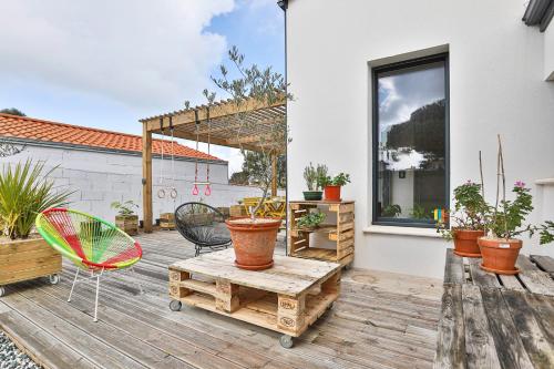 a patio with a table and chairs and potted plants at Brem sur mer - Maison familiale in Brem-Sur-Mer