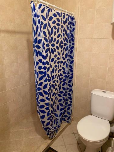 Un baño con inodoro y una cortina de ducha azul y blanca. en Апартамент генерал столетов, en Varna