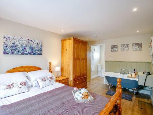 a bedroom with a bed and a bath tub at Wit's End Holiday Cottage in Woodhall Spa