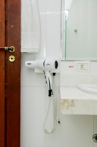 a white hairdryer hanging on a wall in a bathroom at Haras Buona Fortuna in Cotia
