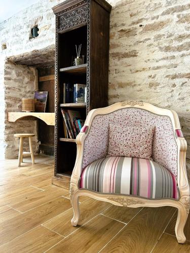 einen Stuhl in einem Zimmer mit Bücherregal in der Unterkunft A l'ombre des Charlemagnes in Pernand-Vergelesses