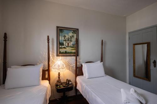 a bedroom with two beds and a lamp and a mirror at Pousada Solar da Inconfidência - fácil acesso a Praça Tiradentes in Ouro Preto