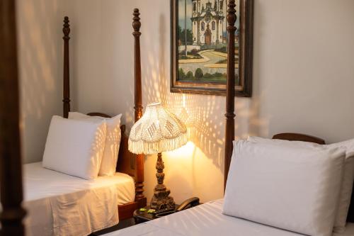 a bedroom with two beds and a lamp and a picture at Pousada Solar da Inconfidência - fácil acesso a Praça Tiradentes in Ouro Preto