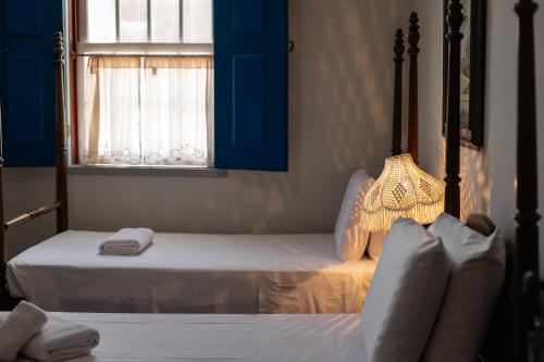 a bedroom with two beds and a window at Pousada Solar da Inconfidência - fácil acesso a Praça Tiradentes in Ouro Preto