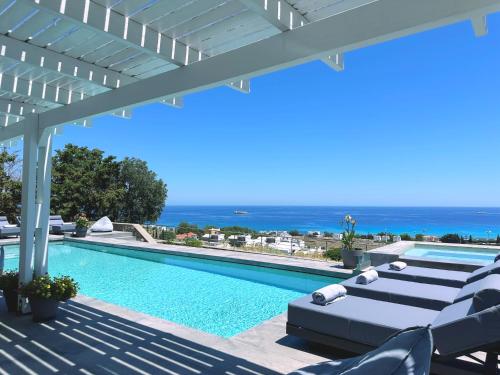 a swimming pool with lounge chairs and the ocean at Solis Lindos Villa in Lindos