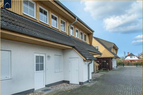 a row of houses with white doors and a driveway at Förster-Schrödter-Str 10-14 Strandbrise in Ostseebad Koserow