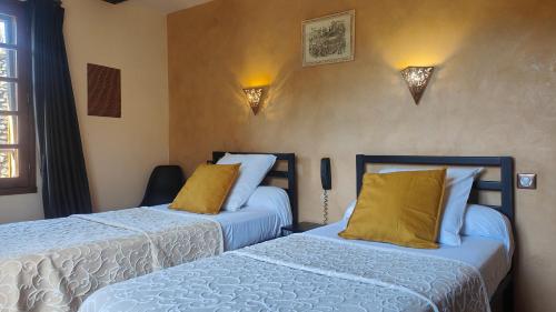 a bedroom with two beds with yellow pillows at Auberge Saint Jacques in Conques