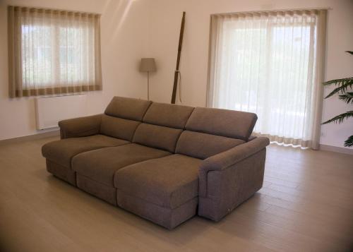 a brown couch in a living room with two windows at Ca' del Mar in Minturno