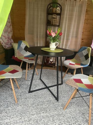 a table with chairs and a vase with flowers on it at Hotel Eulenhof in Gransdorf