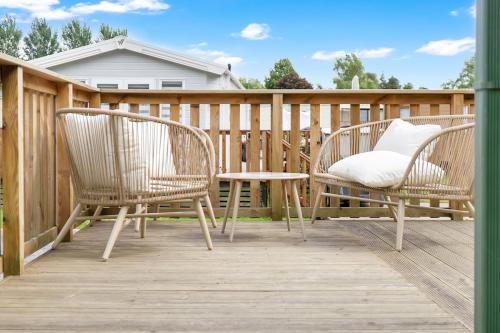 two chairs and a table on a wooden deck at The Chester-2 bed Static Caravan in Oxnam