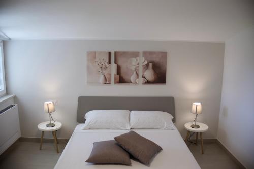 a white bedroom with a bed with two lamps at Ca' del Mar in Minturno