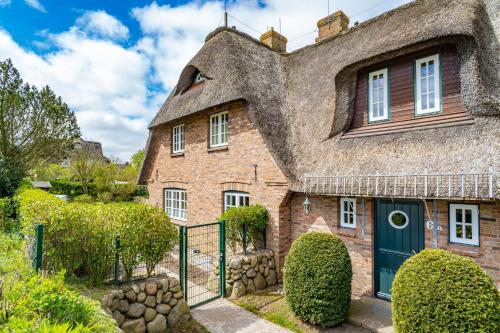 an old brick house with a thatched roof at Haus Daanshoog in Keitum