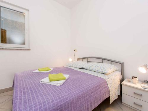 a bedroom with a purple bed with towels on it at Apartment in Vrbnik - Insel Krk 13615 in Vrbnik