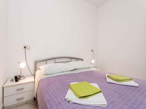 a bedroom with a purple bed with towels on it at Apartment in Vrbnik - Insel Krk 13615 in Vrbnik