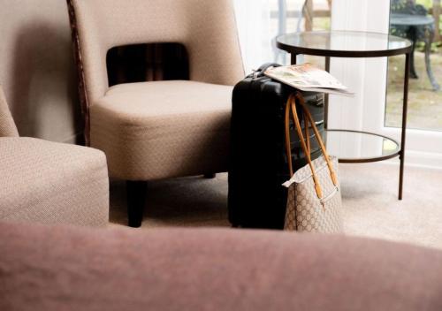 a suitcase sitting next to a chair and a table at Lakeside Hotel and Spa in Newby Bridge