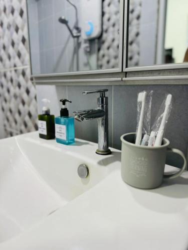 a bathroom sink with a cup of toothbrushes at Best Day Homestay ! in Kangar