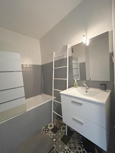 une salle de bain avec un lavabo, une baignoire et un miroir dans l'établissement Le Sombrero, central avec parking, à Limoges