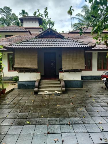 a house with a blue door and a tile roof at Utthara Tharavadu in Irinjālakuda