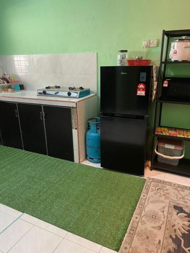 a kitchen with a black refrigerator and a stove at Homestay Taman Delima Paka in Kampong Gong Gemia
