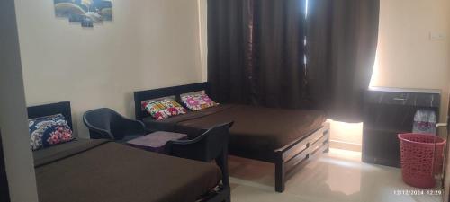 a room with a bed and a table and a bed and a desk at Calangute Pristine Guest House in Calangute