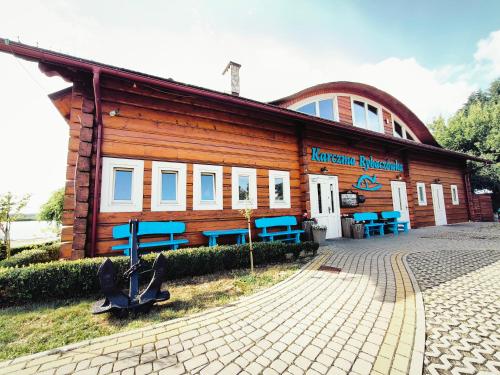 a building with blue benches in front of it at Karczma Rybna Rybaczówka Marina B&B in Świnoujście